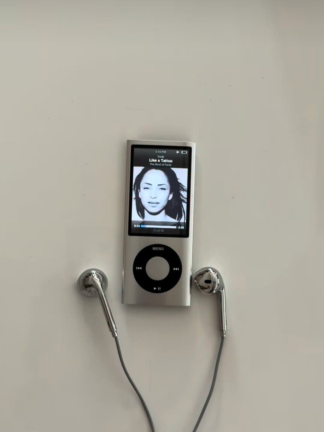 Chrome Buds earbuds with grey cable laid beside a silver iPod nano on a white desk