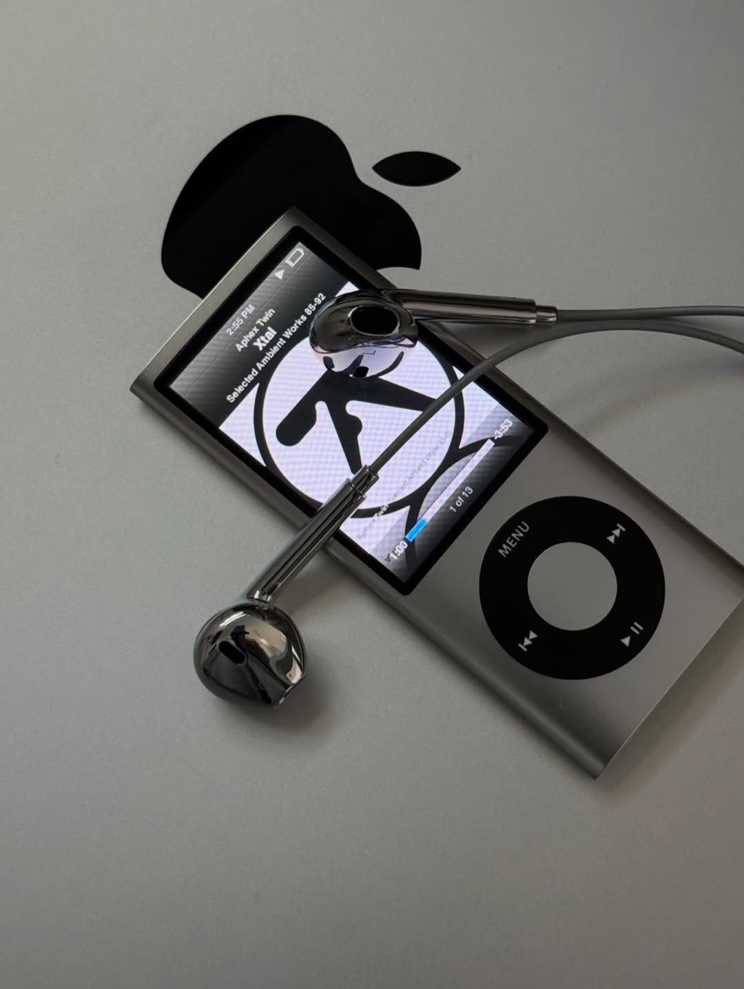 Chrome Buds earbuds draped across a silver iPod nano lying on a laptop